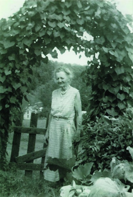 Grandma raised beautiful vegetable gardens.  She is standing in front of a trellis with a huge bean vine on it.